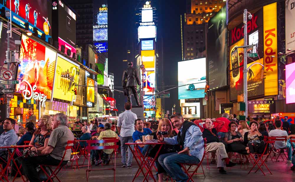 People sitting in Times Square with Broadway Posters