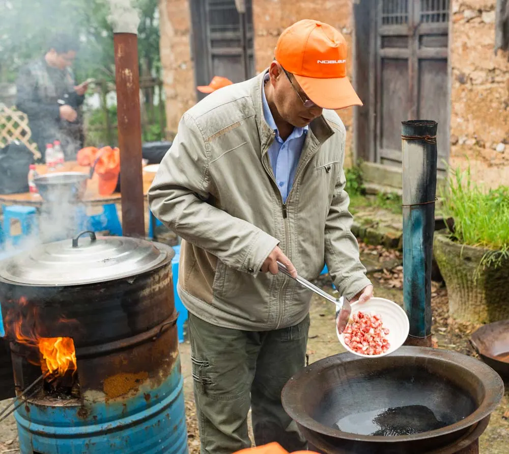 Local man cooking food in China Chinese market Cost of Travel in China